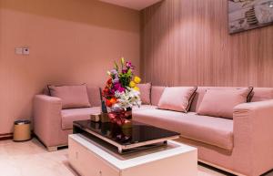 a living room with a couch and flowers on a table at City Park Hotel Apartments in Muscat