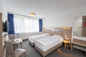 een hotelkamer met 2 bedden en een bureau bij Hotel & Gästehaus Rostock Lütten Klein in Rostock