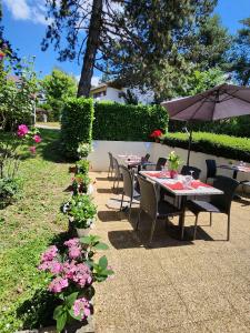 einen Tisch und Stühle mit Sonnenschirm in einem Garten in der Unterkunft Campanile Annecy - Cran Gevrier in Annecy