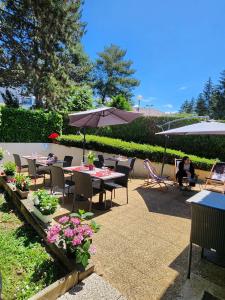 eine Terrasse mit Tischen, Stühlen und Sonnenschirmen in der Unterkunft Campanile Annecy - Cran Gevrier in Annecy