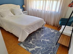 - une chambre avec un lit blanc et un tapis bleu et blanc dans l'établissement Villa Margarida, à Viana do Castelo