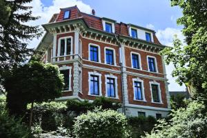 ein großes rotes Backsteingebäude mit blauen Fenstern in der Unterkunft Ferienwohnung Villa Funcke in Eisenach