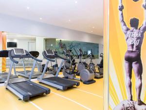 ein Fitnessstudio mit Laufbändern und einem Mann an der Wand in der Unterkunft Novotel Brussels City Centre in Brüssel