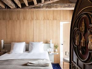 um quarto com uma cama e uma parede de madeira em Domaine Reine Margot Paris - Issy MGallery Collection em Issy-les-Moulineaux