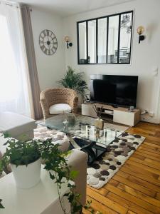 un salon avec une table en verre et une télévision dans l'établissement Résidence Renan - Paris Porte de Versailles, à Issy-les-Moulineaux