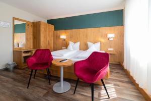 a hotel room with a bed and two pink chairs at Hotel & Gasthof Richard Held in Regensburg