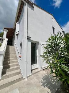 um edifício branco com escadas ao lado de uma casa em Appartement 2 pIeces rdc de villa Mouans Sartoux em Mouans-Sartoux