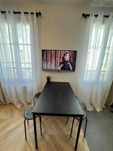 una mesa negra y sillas en una habitación con ventanas en Superbe appartement neuf 2 pièces Vincennes pte de Paris, en Montreuil