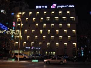 Jinjiang Inn Tianjin Development Zone Branch في Binhai: مبنى فيه سيارات تقف امامه ليلا