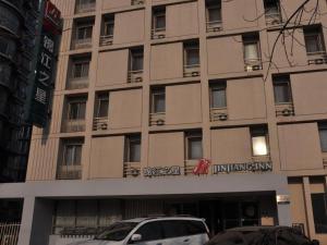 Jinjiang Inn Tianjin Development Zone Branch في Binhai: مبنى كبير فيه سيارات تقف امامه