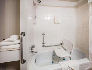 a white bath tub with a chair in a bathroom at Howard Johnson Hotel by Wyndham Victoria in Victoria