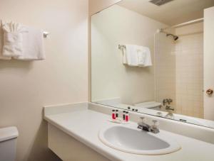 a white bathroom with a sink and a mirror at Howard Johnson Hotel by Wyndham Victoria in Victoria