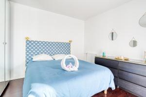 a bedroom with a blue bed with a white purse on it at "Le Sérénity ", Appartement spacieux ,balcon, parking privé gratuit, proche CDG et Stade de France in Stains