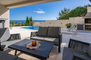 eine Terrasse mit einem Tisch, Stühlen und einem Pool in der Unterkunft Apartment TESI in Dugi Rat