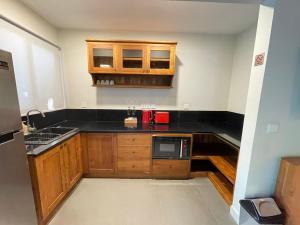 a small kitchen with wooden cabinets and a microwave at Bali Santi Bungalows in Candidasa