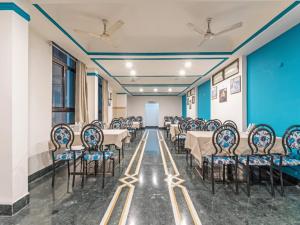 een kamer met tafels en stoelen en blauwe muren bij Hotel Indore Palace - Guest Centric Hotel in Shirdi