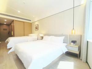 - 2 lits dans une chambre d'hôtel avec des draps blancs dans l'établissement CM Serviced Apartment Shenzhen Dongmen, à Shenzhen