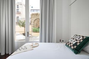 - une chambre avec un lit blanc et une grande fenêtre dans l'établissement Chic & Basic Born Boutique Hotel, à Barcelone