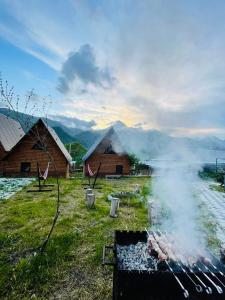 un grill avec fumée dans un champ à côté des bâtiments dans l'établissement Guesthouse Elli & Cottages, à Kazbegi