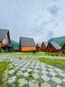 un groupe de bâtiments avec des montagnes en arrière-plan dans l'établissement Guesthouse Elli & Cottages, à Kazbegi