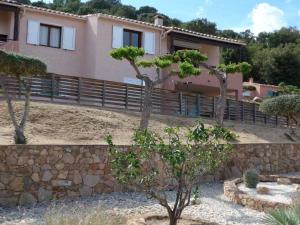 uma casa com uma parede de pedra e árvores num quintal em Domaine San Sebastiano em Porto-Vecchio