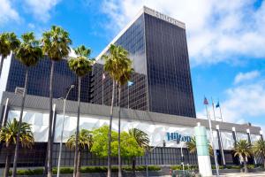 um edifício alto com palmeiras em frente em Hilton Los Angeles Airport em Los Angeles