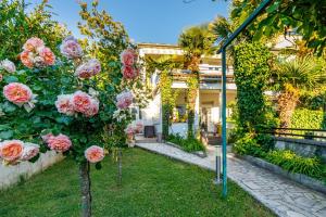 um jardim com rosas rosas em frente a uma casa em Jozefina Luxury, 100 m from the beach em Poreč