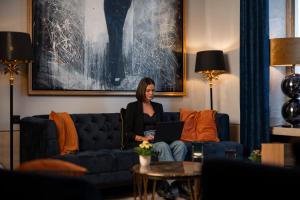 a woman sitting on a couch with a laptop at Boutique Hotel Germania in Munich