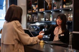 a woman standing at a bar talking to a customer at Boutique Hotel Germania in Munich