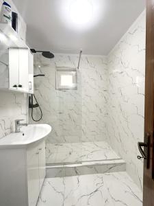 a bathroom with white marble walls and a sink at B7 Apartament in Ocna-Mureşului