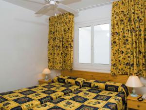 a bedroom with a bed with yellow curtains and a window at BelleVue Aquarius in Puerto del Carmen