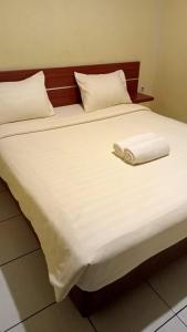 een bed met een witte deken en kussens erop bij Guest House Permata Tawakal in Jakarta