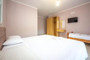 a bedroom with a large white bed and a tv at Blu Horizon Hotel Gjipe in Dhërmi