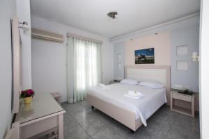 una camera bianca con un letto bianco e una finestra di Ilion Hotel a Naxos Chora