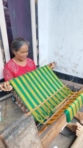 a woman is working on a green and yellow at Hide and Seek in Tetebatu