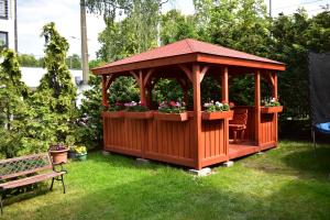 un kiosque en bois avec des fleurs et un banc dans l'établissement Willa Bea, à Gdańsk