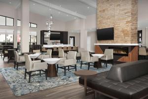 een lobby met tafels en stoelen en een open haard bij Residence Inn by Marriott Galveston Island in Galveston