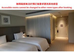 twee bedden in een hotelkamer met een advertentie voor een toegankelijke kamer kan niet bij Greet Inn in Kaohsiung