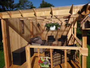 a wooden pergola with two chairs and a table at B&B Le bruissement in Bièvre