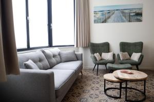 ein Wohnzimmer mit einem Sofa und 2 Stühlen in der Unterkunft Maison d'O in Ostende