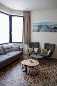 ein Wohnzimmer mit einem Sofa, 2 Stühlen und einem Tisch in der Unterkunft Maison d'O in Ostende