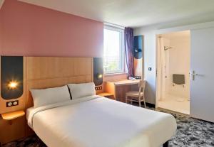 una camera d'albergo con letto, scrivania e finestra di B&B HOTEL Orly Rungis Aéroport 3 étoiles a Rungis