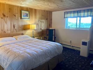 een slaapkamer met een groot bed en een raam bij Castle Rock Country Inn in Ingonish Beach