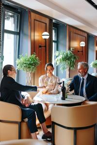 a group of people sitting around a table in a restaurant at Hotel Balkan in Belgrade