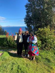 un grupo de tres personas posando para una foto en Amantani Resorts, en Estanciasuyo