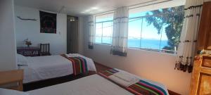 1 dormitorio con 2 camas y ventana grande en Amantani Resorts, en Estanciasuyo