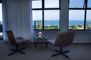 2 stoelen en een tafel in een kamer met ramen bij Ocean Vista Boutique Guest House in Durban