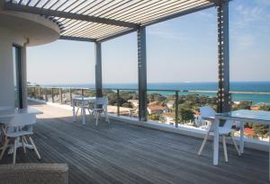 a balcony with tables and chairs and a view of the ocean at Ocean Vista Boutique Guest House in Durban