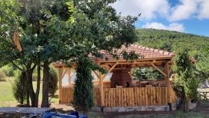 a wooden gazebo in a field with trees at Tomiceva Koliba Rtanj 4 in Rtanj