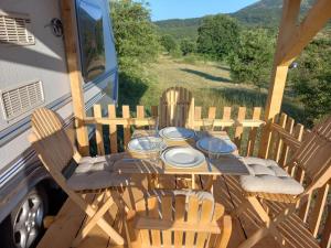 a table and chairs on a porch with a bus at Tomiceva Koliba Rtanj 4 in Rtanj